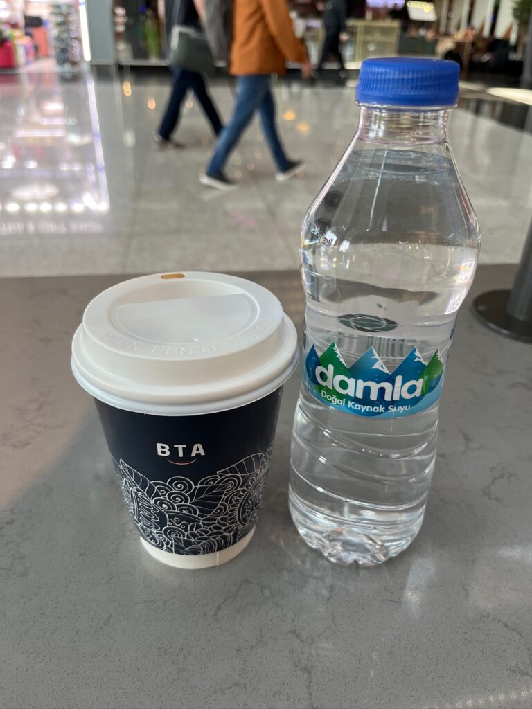 トルコの空港でコーヒーと水を置いて休憩している様子。海外旅行中の通信確認の場面